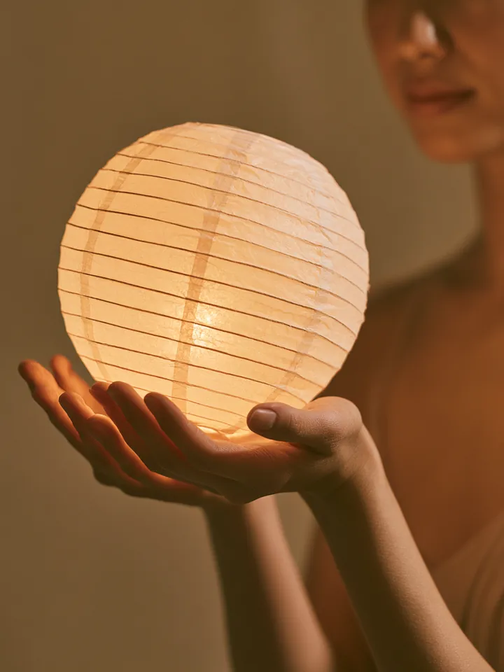 Hands cupping a small glowing paper lantern, symbolizing a Happy Money loan used thoughtfully for the holidays